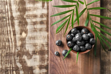 Bowl with fresh acai berries on wooden table