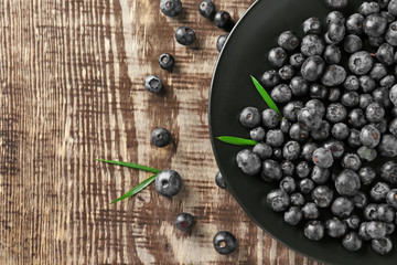 Plate with fresh acai berries on wooden table