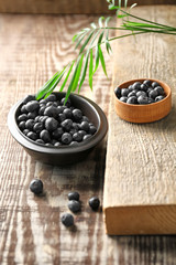 Bowls with fresh acai berries on wooden table