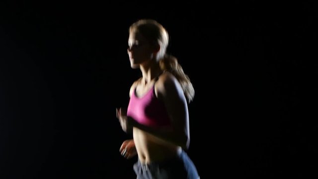 Girl with long hair runs confidently on a black background. Close up