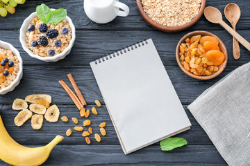 Composition of tasty oatmeal with berries and notebook on wooden background