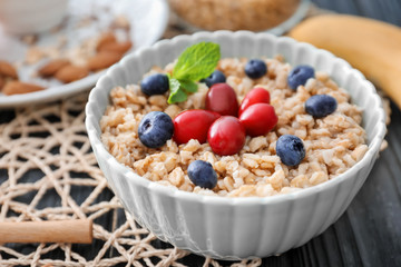 Tasty oatmeal with berries in bowl on table