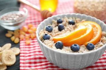 Tasty oatmeal with fruit in bowl on table
