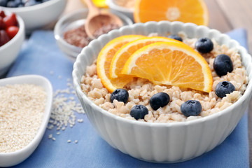 Tasty oatmeal with fruit in bowl on table