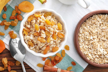 Tasty oatmeal with raisins in bowl on table