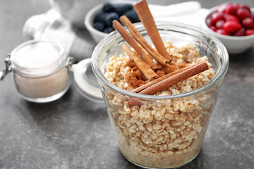 Tasty oatmeal with cinnamon sticks in glass on table