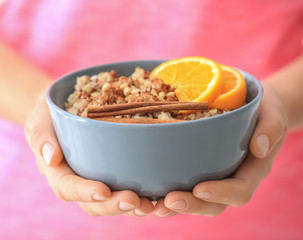 Woman holding bowl with nutritious oatmeal, close up