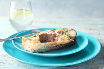Ceramic plate with fried fish steak on blurred background