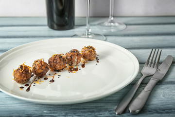 Plate with tasty sausage cheese balls on table