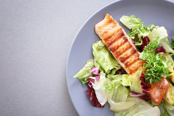 Plate with slice of delicious salmon on table