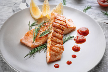 Delicious slices of salmon with sauce on plate, close up