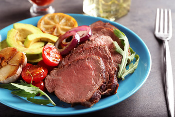 Plate with sliced delicious steak and vegetables, close up