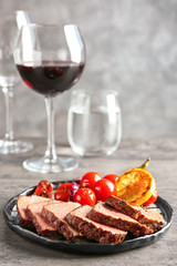 Plate with sliced delicious steak and vegetables on table