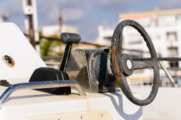Old and worn steering wheel and throttle on a small fishing boat