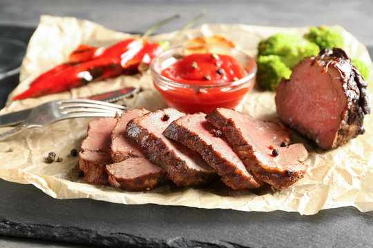 Sliced tasty steak with sauce on slate plate