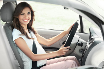 Pregnant young woman driving car