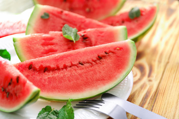 Plate with slices of tasty watermelon on table