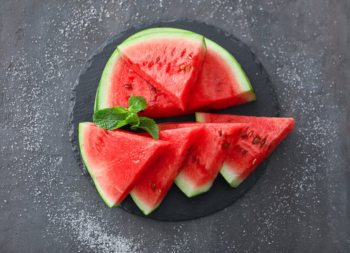 Slate plate with slices of tasty watermelon on table
