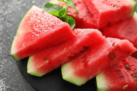 Slate plate with slices of tasty watermelon on table, closeup