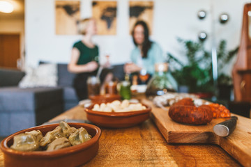 two young women are relaxing and chatting together with wine and ready to eat food	