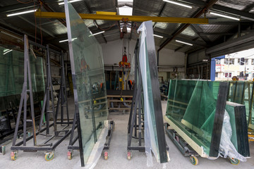 Interior view of a glazier factory with glass panels on trolleys awaiting cutting