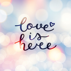 love is here lettering, vector handwritten text on blurred lights