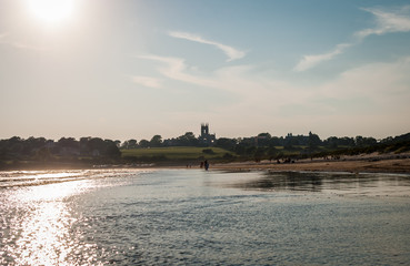 Beach waves crashing. Isolated castle background. Ocean beach shore. People walking on beach. Clear sky background. © taurusnyy