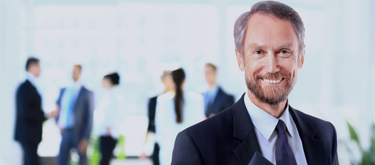 Happy mature business man looking at camera with satisfaction at office