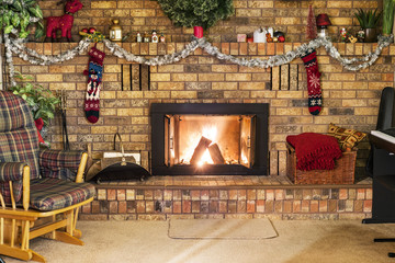 Roaring fire in a vintage brick fireplace decorated for Christmas, with piano, rocking chair and cozy decor