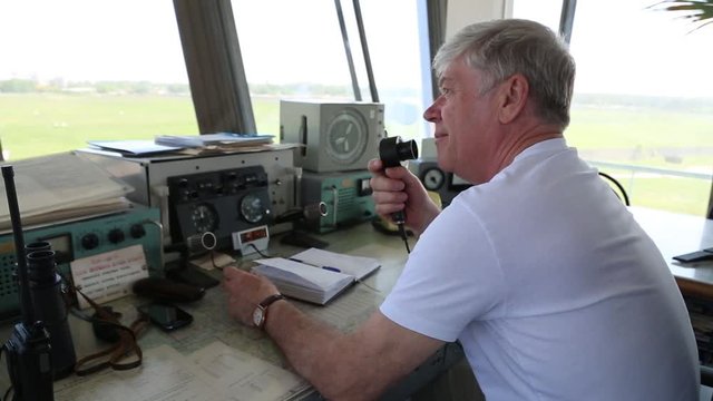 The airport dispatcher communicates with the pilot on the radio.