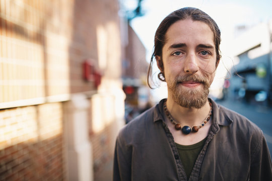 Portrait of young traveler man standing on city sidewalk