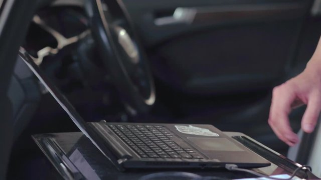 Car expert using notebook for auto diagnostic. Computer diagnostics car engine