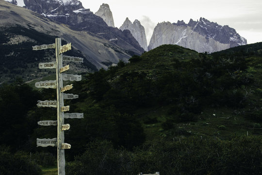 Wooden Milepost Sign, Green Hills and Tall Granite Peaks in the distant Background