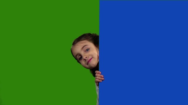 Child looks out from behind an empty board. Green screen. Slow motion