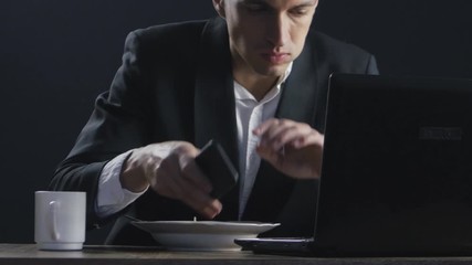 Busy multitasking businessman uses a laptop, smartphone and eats, timelapse - Powered by Adobe