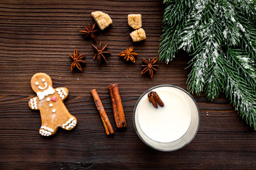 Merry christmas in winter evening with alcohol drink. Eggnog with gingerbread cookie, cinnamon and spruce on wooden desk background top view