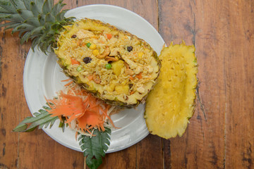 Pineapple fried rice on white dish on wood table.