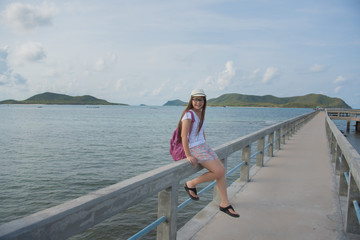 Portrait of young asian woman with backpack  on the old sea pier at Rayong beach in Thailand. Have a vacation and travel concept.