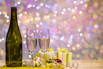 Bottle of champagne and glasses are placed together with a gift box and shiny balls. Space on top right for your wording.