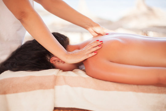 Spa and massage. Pretty woman in spa salon in sunny beach get face and back massage. High quality.