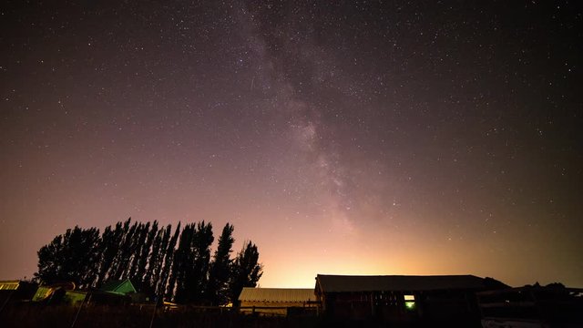 Spendid time lapse view of starry night sky in Idaho showing rural outbuildings and tree line silhouettes