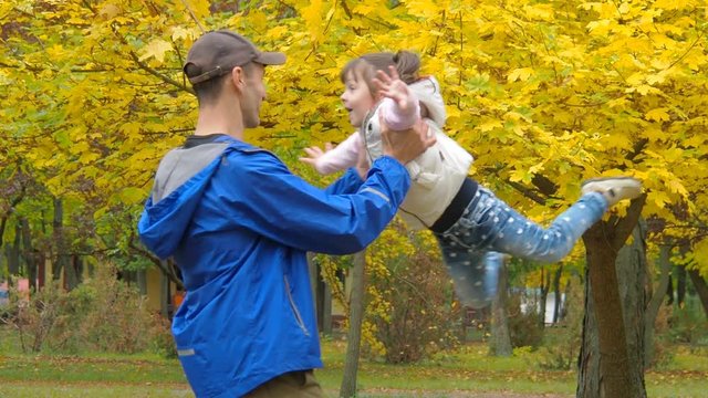 A man is circling a child in nature. Papa circling a small daughter in an autumn park.