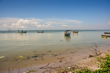 Fototapeta na wymiar Vietnamese Fishing Boats in Calm Azure Sea by Beach