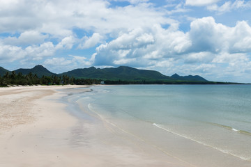 Quiet beach with clouds and mountains.