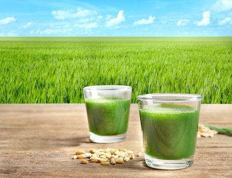 Wheat grass shots and grain on wooden table