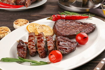 Plate with yummy grilled steaks on wooden table