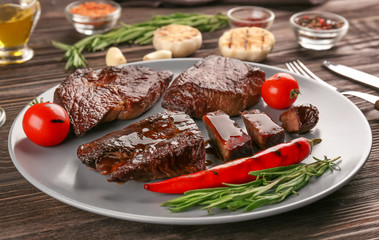 Plate with yummy grilled steaks on wooden table