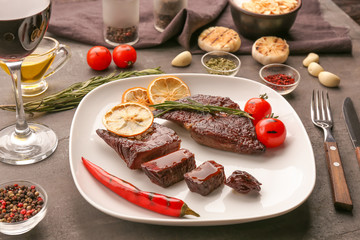 Plate with delicious grilled steaks on kitchen table