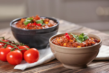 Bowls with delicious chili con carne on table