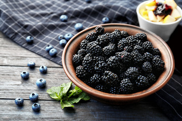Bowl with delicious ripe blackberries on wooden table